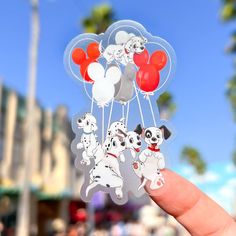 a person holding up some stickers with dogs and balloons attached to them in the air