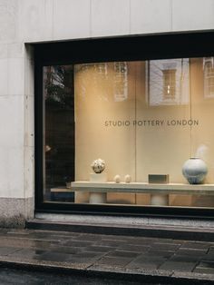 a store window with vases in it on the side walk next to a sidewalk