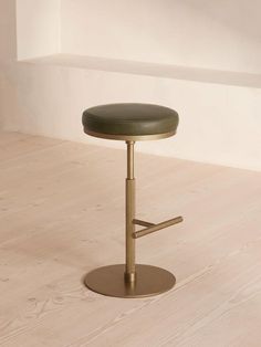 a stool with a foot rest in front of a white wall and wood flooring