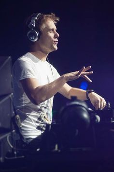 a man with headphones on sitting in front of a dj mixer at a concert