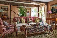 a living room filled with lots of furniture and paintings on the wall next to a window