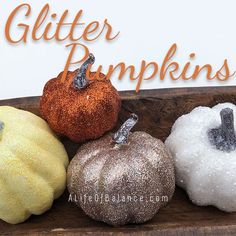 four glitter pumpkins sitting on top of a wooden board with the words glitter pumpkins above them