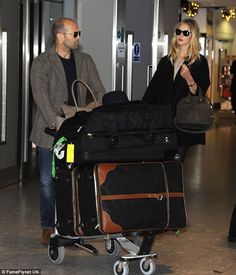 a man and woman pulling luggage through an airport