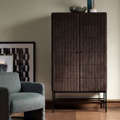 a brown cabinet sitting next to a blue chair in a living room with hardwood floors