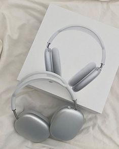 a pair of headphones sitting on top of a white sheet next to a book