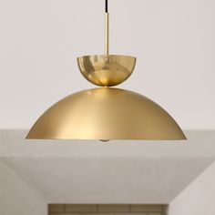 a gold colored light fixture hanging from the ceiling in a room with white brick walls