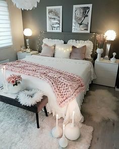 a white bed sitting in a bedroom next to two nightstands with candles on them