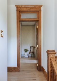 an open door leading into a room with wood floors and white walls in the background