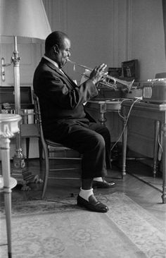 a man sitting in a chair playing a trumpet