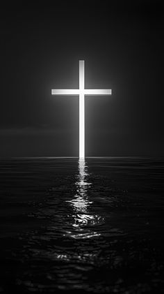 a large cross in the middle of water with a bright light shining on it's side