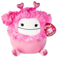 a pink stuffed animal with hearts on it's head and eyes, sitting in front of a white background