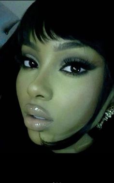 a close up of a person with dark hair and makeup on her face, wearing silver jewelry