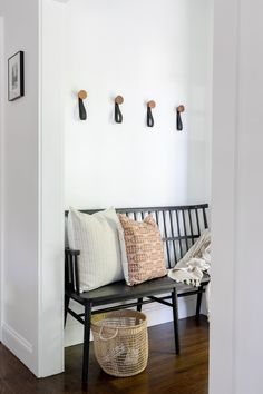 a wooden bench sitting in the middle of a room next to a wall with hooks on it