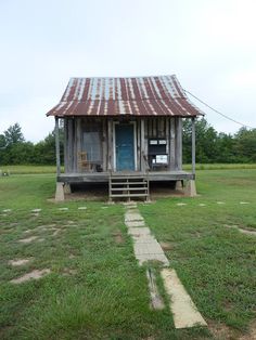 an old outhouse with a rusty tin roof and steps leading up to the door