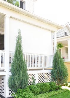 a white house with trees and bushes in the front yard