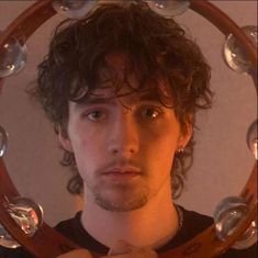 a man with curly hair standing in front of a mirror