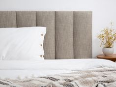 a bed with white sheets and pillows on top of it next to a wooden night stand