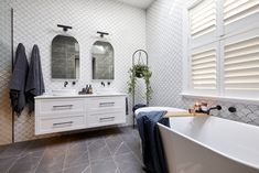 a large bathroom with two sinks and a bathtub in the center, along with mirrors on the wall