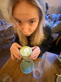 a woman holding a cup of coffee at a table