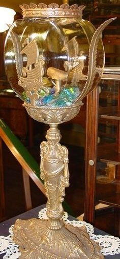 an ornate glass vase on top of a table with gold trimmings and decorations