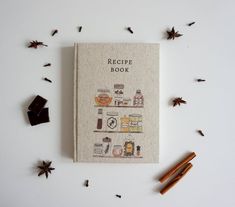 a recipe book surrounded by cinnamon sticks and spices