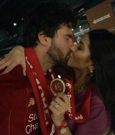 a man and woman kissing each other while wearing red scarfs on their shoulders,