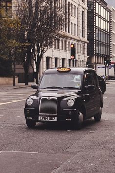 a black taxi cab driving down a street next to tall buildings