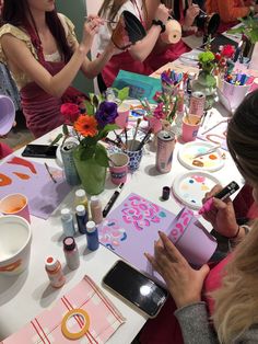 a group of women sitting around a table with crafting supplies on top of it