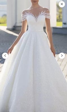 a woman in a white wedding dress standing on a sidewalk