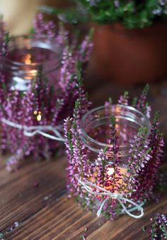 small glass jars filled with purple flowers on top of a wooden table