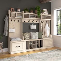 a room filled with lots of white furniture and plants on top of shelves next to a window