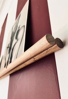 a close up of a wooden object on a wall with pictures behind it and a stick sticking out of the wood