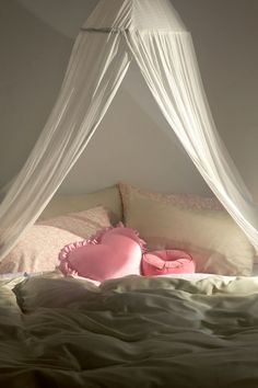 a white canopy over a bed with pink pillows