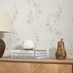 two vases sitting on top of a wooden table next to books and a lamp