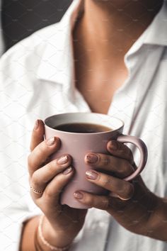 a woman holding a cup of coffee in her hands