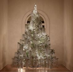 a christmas tree made out of glass bottles in front of a window with an arched doorway