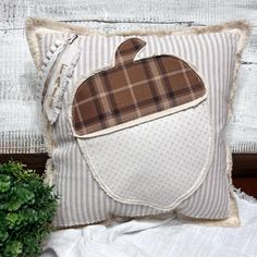 an apple pillow on top of a bed next to a potted plant