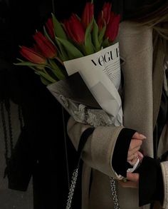 a woman holding a bouquet of red flowers in her left hand and a cell phone in her other hand