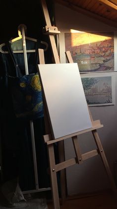 an easel with a white board on it in front of some pictures and paintings