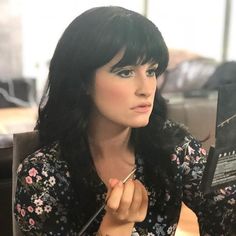 a woman sitting at a table with a book in her hand and writing on it