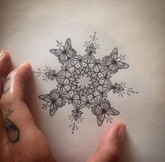 a hand holding a piece of paper with a drawing of a snowflake on it