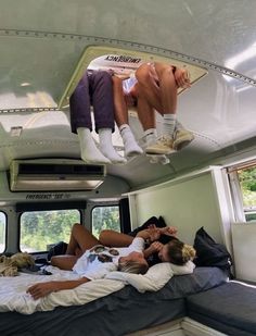 three people hanging upside down from the ceiling in a camper with their feet up