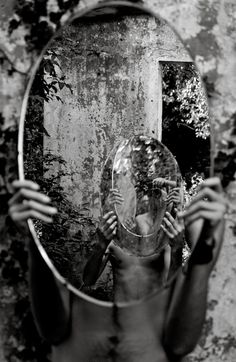 a woman holding a mirror in front of her face