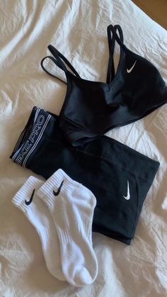 two pairs of nike sports bras and one pair of white socks on a bed