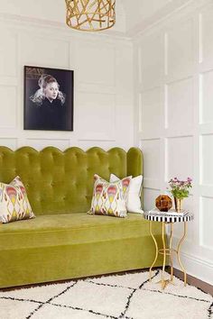 a green couch sitting in a living room next to a table with flowers on it