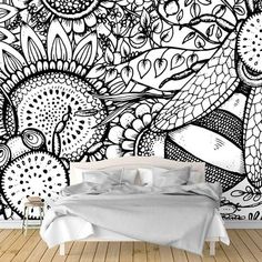 a bed sitting in front of a black and white wall with lots of flowers on it