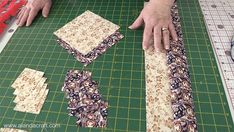 a person cutting up fabric on top of a green cutting board with scissors and tape