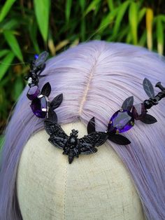 Embrace the dark elegance of the night with this Moth-Inspired Gothic Tiara, meticulously handcrafted in striking black and silver tones. At the center of this bewitching crown sits a stunning black moth charm, embodying the mysterious allure of nocturnal creatures. Flanking the moth, shimmering purple rhinestones add a touch of captivating sparkle, while black sword charms on each side enhance the tiara's edgy, gothic appeal. The tiara is adorned with an array of deep purple round and teardrop Gothic Tiara, Elf Headpiece, Fairy Tiara, Nocturnal Creatures, Purple Chandelier, Gothic Costume, Purple Fairy, Dark Elegance, Fantasy Wedding