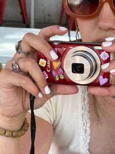 a woman taking a photo with her camera in front of her face and wearing sunglasses