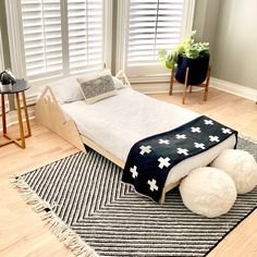 a bed with a black and white blanket sitting on top of it next to two windows